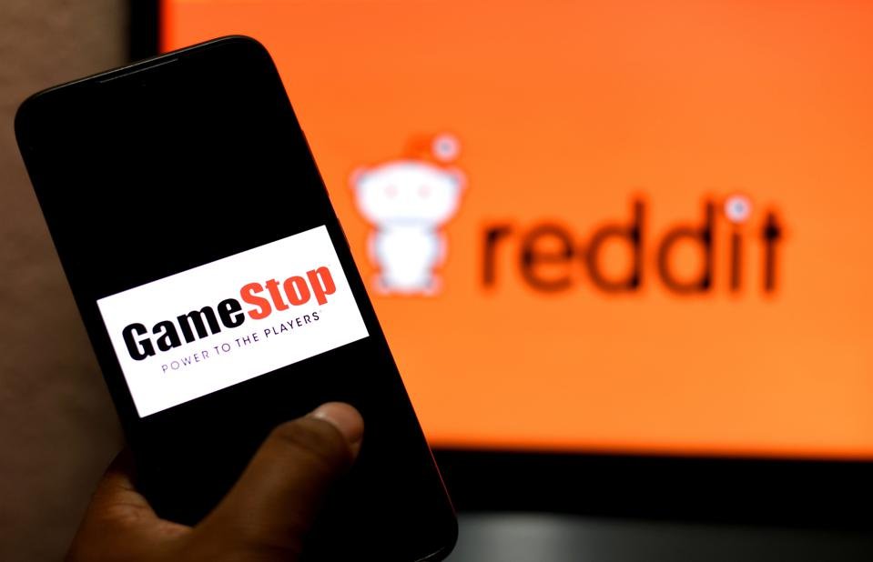 Illustration a GameStop logo seen displayed on a smartphone and a Reddit logo in the background.