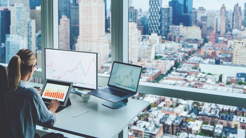 Businesswoman sitting at panoramic skyscraper office viewing financial graphs