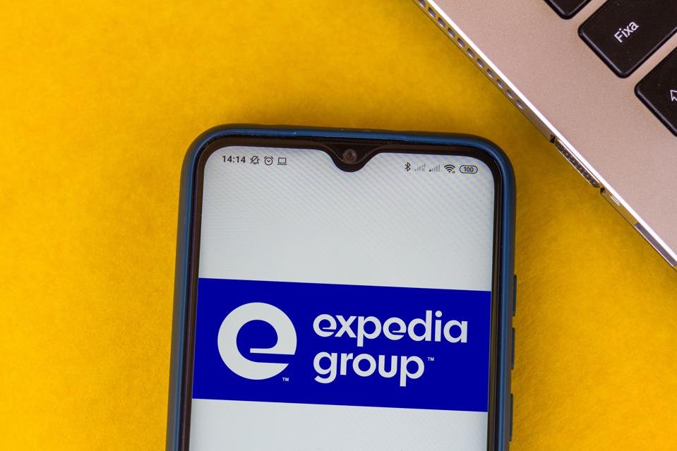 In this photo illustration the Expedia Group logo seen...